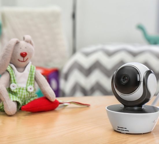 Baby monitor and toy on table in room, space for text. CCTV equipment