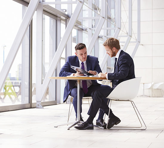 Two businessmen discussing work in the office - R Collins & Co Insurance Brokers