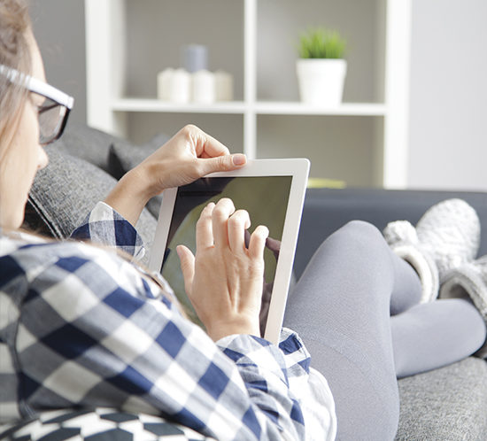 A woman using her tablet device at home - Lagentium Insurance Brokers