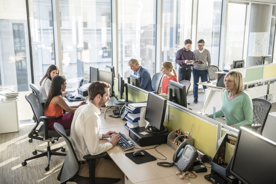 Office workers at desks using computers in modern office