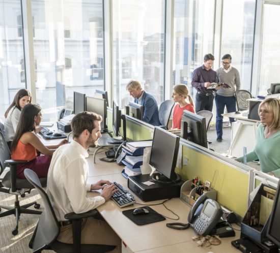 Office workers at desks using computers in modern office