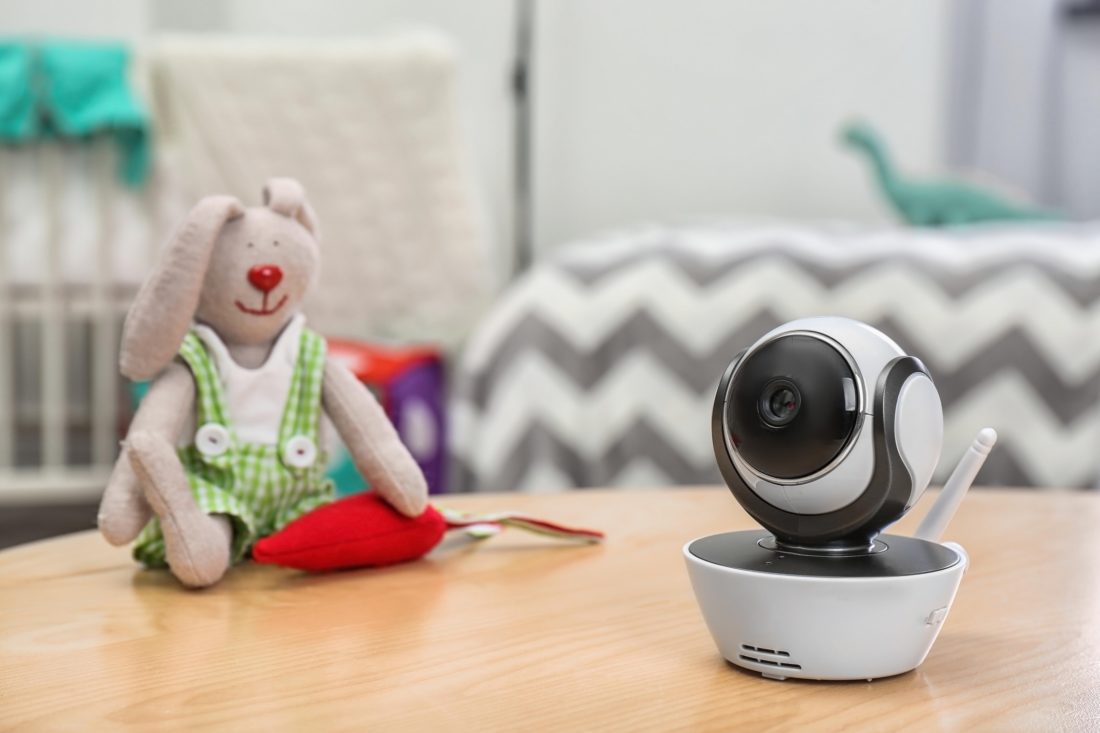 Baby monitor and toy on table in room, space for text. CCTV equipment